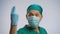 Funny man wearing scrubs and face mask pretending to be proctologist, crazy joke
