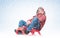 Funny man in winter clothes rides on a sled around snow. Christmas holiday concept