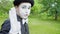 Funny mime is crooking on camera in the park