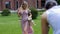 funny mother and daughter in pink dresses in nature on a green meadow in summer and they are photographed by a