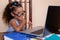 Funny multiracial small girl wearing glasses and using a laptop