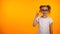 Funny nerd schoolgirl raising finger up isolated on orange background, good idea