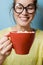 Funny Nerd young woman with a red mug with cocoa and marshmallow