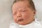 Funny newborn baby boy looking at camera with distrust. Portrait of cute winking kid