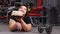 Funny obese woman holding delicious cake in gym. Fat woman in black t-shirt lying on floor of empty gym with a dumb-bell