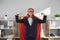 Funny office worker in red superhero mask and cape demonstrating can-do attitude