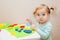 Funny one year old girl playing with colorful dough at home or daycare.