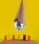 Funny party. Small jelly bears stay on scene and big toy disco ball in waffle ice-cream cone hanging above. Vertical photo, yellow