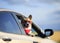 Funny passenger puppy dog red Corgi in the sunscreen glasses pretty sticks out his face with his tongue sticking out of the car