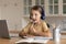 Funny pensive little girl in headphones studying online at home