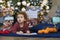 Funny pensive little girl writing letter to santa. kid making a wish, gift, present on new year eve.