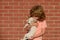 Funny photo of happy child hugging beautiful puppy dog on wall. Kid with pets.