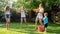 Funny photo of happy family with children playing and splashing water with water guns and garden hose at hot sunny day
