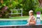 Funny photo of little child relaxing in outdoor swimming pool