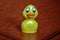 Funny plastic toy, little yellow duckling on a brown background. Close-up. Copy space