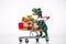 A funny plastic tyrannosaurus rides on a shopping cart full of Christmas gifts