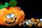 Funny plush toy in the shape of a halloween pumpkin with lots of chocolate balls around it, covered with nice smiley faces