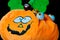 Funny plush toy in the shape of a halloween pumpkin with lots of chocolate balls around it, covered with nice smiley faces