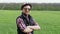 Funny portrait of cool farmer puts on a hat in the green wheat field