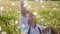 funny portrait of a five year old boy stands on a field of dandelions and catches soap bubbles from a toy gun at sunset