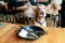 Funny portrait of happy cocker spaniel puppy sitting on chair in caffe with ears stretched wide and empty plate on a table