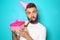 Funny portrait of man with Birthday gift and party whistle on color background