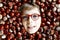 Funny portrait of preteen or school kid boy with glasses with lots of chestnuts. Smiling happy child having fun on