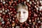 Funny portrait of preteen or school kid boy with lots of chestnuts. Smiling happy child having fun on autumn day with a