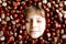 Funny portrait of preteen or school kid boy with lots of chestnuts. Smiling happy child having fun on autumn day with a