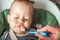 Funny portrait of toddler eating close-up. Complementary feeding of child with porridge at 9 months. Zucchini, cauliflower, brocco