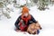 Funny portrait of woman with her two dogs wrapped in red checkered plaid on a snow in winter coniferous forest