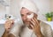 Funny portrait of young happy and attractive camp gay man in bathroom applying moisturizer eye patch facial product with head