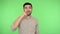 Funny positive brunette man picking his nose, pulling out boogers and making stupid grimaces. green background, chroma key