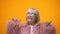 Funny positive elderly female in pink coat making rocker gesture, having fun