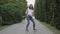 Funny pregnant woman dancing on path of the park in the alley of trees