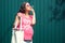 Funny pregnant woman with eco shopping bag holding pink flower like cigarette on green background. Positive pregnancy, zero waste