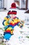 Funny preschool boy in colorful clothes making a snowman