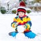 Funny preschool boy in colorful clothes making a snowman
