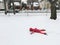 Funny preschool child girl in warm clothes pink red jacket lying in snow during cold winter day with her face down