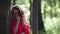 funny pretty woman in red dress is standing near tree in forest