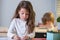 Funny pupil in classroom at school. Little girl sitting at desk in class. Portrait of young schoolgirl studying and