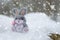 Funny rabbit in snow, christmas or easter concept. A toy gray hare sits in a snowdrift against the backdrop of a forest