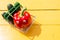 Funny red paprika with eyes and green cucumbers in the small supermarket basket on the yellow background. Vegetarian concept