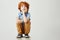 Funny redhead little boy sitting on box, holding head with hand, looking in camera with happy expression, posing for