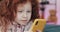 Funny redhead little girl with yellow smartphone lies on the bed and using smartphone. Communication, playing, app.