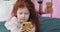 Funny redhead little girl with yellow smartphone lies on the bed and using smartphone. Communication, playing, app.