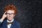 Funny redhead smart kid boy in classroom on chalkboard background with science formulas. Back to school concept