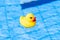 Funny rubber ducky. Yellow inflatable toy for kids swim in blue water of summer pool. Minimal summer concept