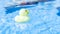 Funny rubber ducky. Yellow inflatable toy for kids swim in blue water of summer pool. Minimal summer concept