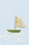 Funny sailboat made of flowers petals and chamomiles on light blue background. Adventure, creativity, holidays concept